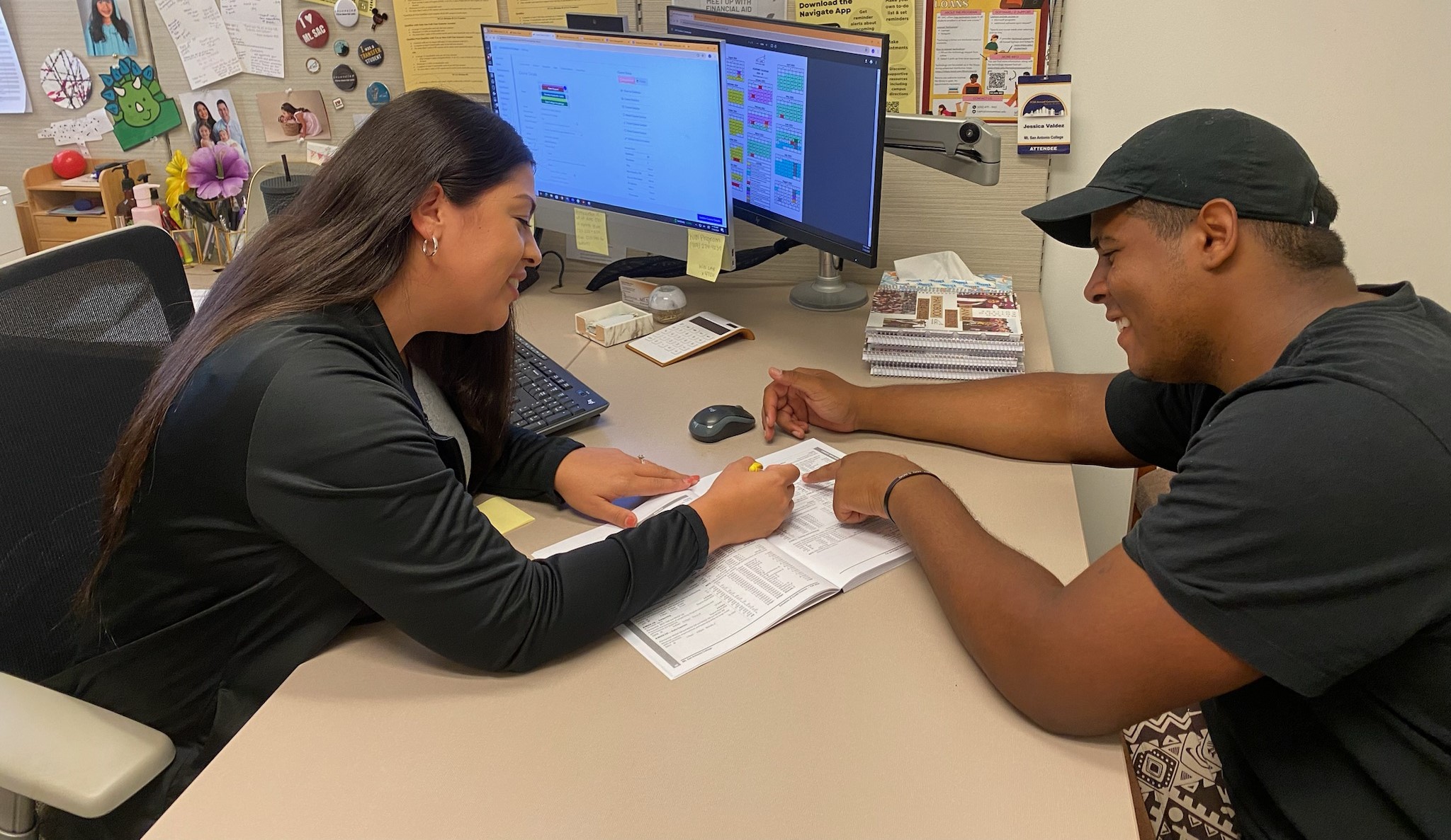 counselor speaking to student seated at a desk 